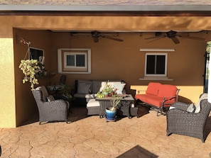 Eine Terrasse im Freien mit Korbmöbeln, einem roten Sofa und Topfpflanzen.