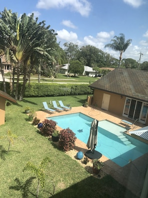 Ein Garten mit Schwimmbad, Liegestühlen und einer kleinen Terrasse.