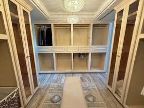 Un dressing avec de nombreux compartiments de rangement, une tringle à vêtements et un tapis décoratif orné de motifs d’étoiles de mer et de coquillages.