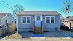 Une maison de plain-pied avec un porche à l’avant, un garage et un petit jardin devant.