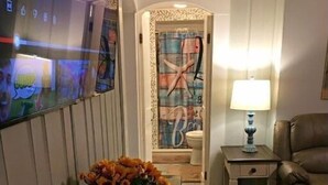 Un salon moderne avec un long banc en bois, un téléviseur fixé au mur, une lampe sur une table d’appoint et un canapé en cuir marron.