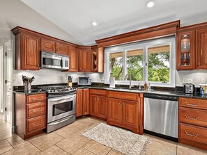 Enjoy cooking in this well-equipped kitchen with a large window offering a view of the outdoors.