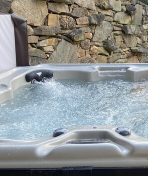 Relax in a modern hot tub against a natural stone backdrop.