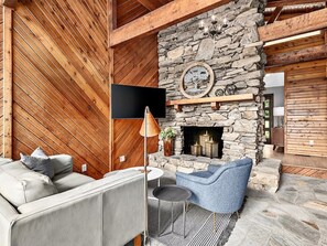 Cozy space with a stone fireplace, comfortable seating area, and a flat-screen TV.