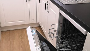 A modern kitchen with white cabinets, a black countertop, and a dishwasher. - ATIC, PRIVATE TERRACE, 2 BEDROOMS (Barcelona)