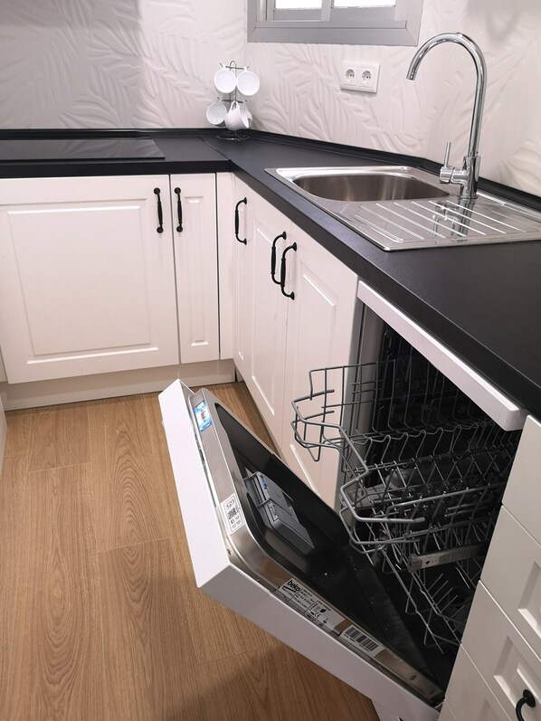 A modern kitchen with white cabinets, a black countertop, and a dishwasher.