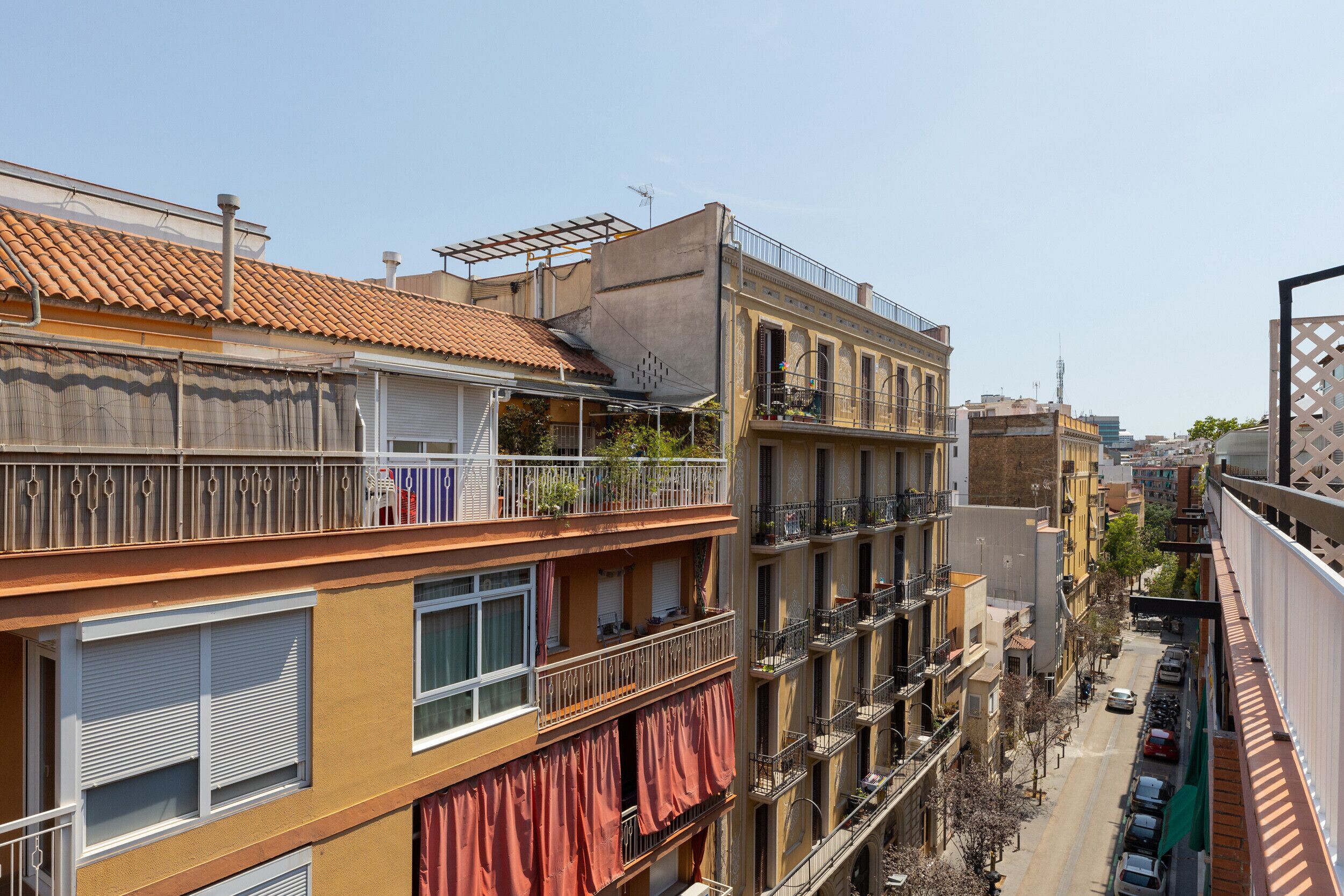 A multi-story building with balconies, a tiled roof, and a street view.