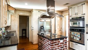 Une cuisine avec un îlot central en briques, des appareils électroménagers en acier inoxydable et des armoires en bois.