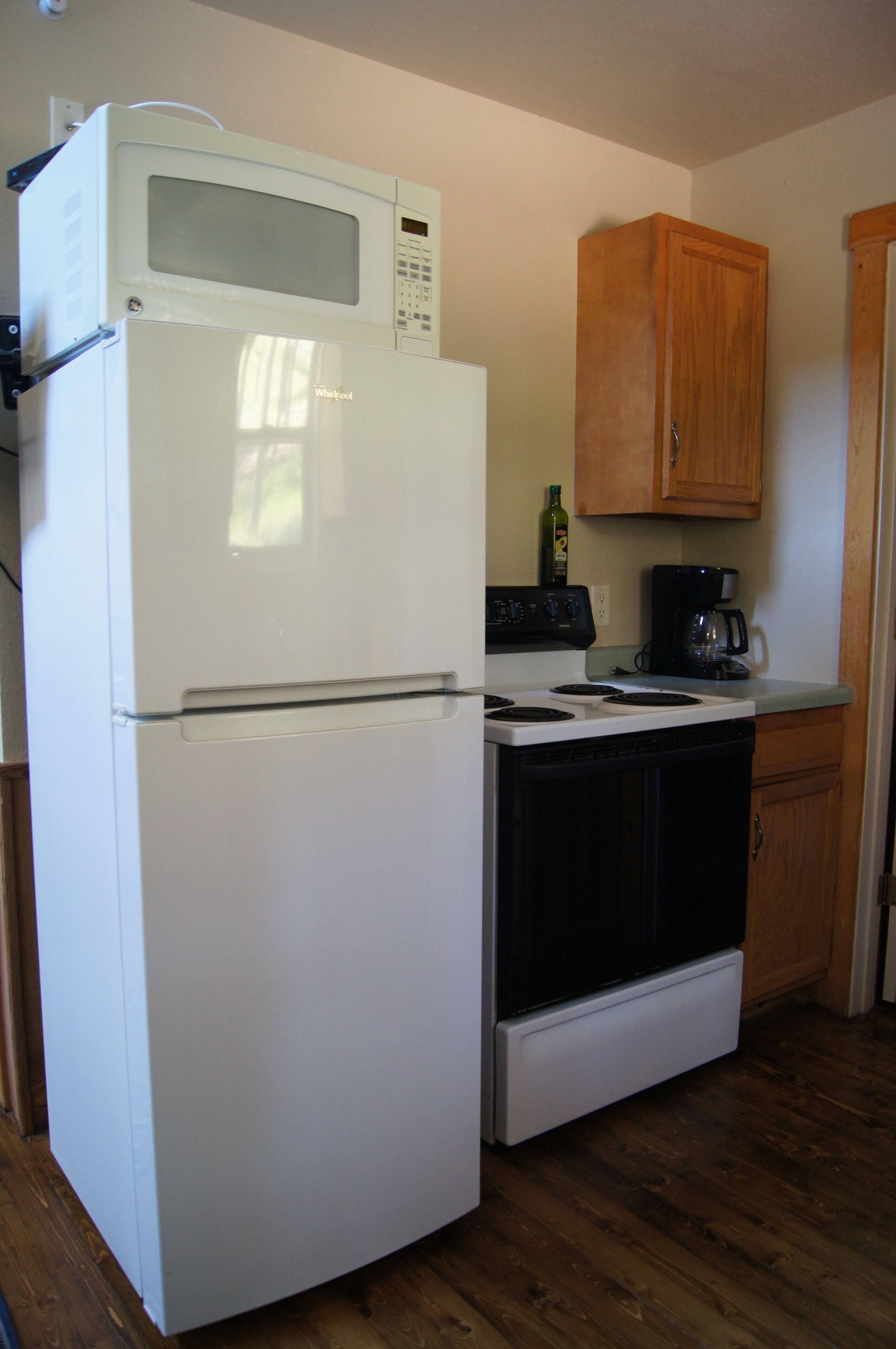 A compact kitchen with a white refrigerator, a stove, and wooden cabinets.