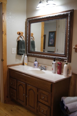 A bathroom with a wooden vanity, a large mirror, and a white sink.