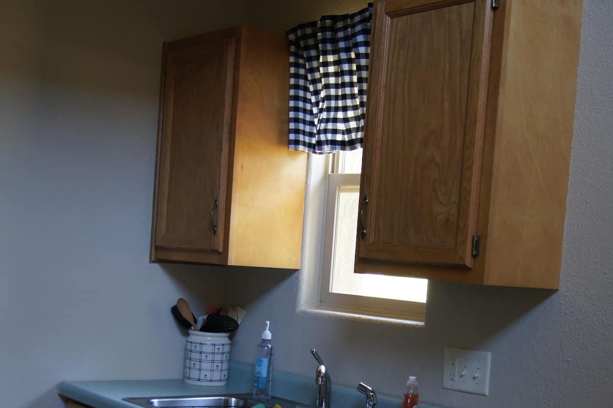 Una cocina con armarios de madera, un ventanal y una encimera con lavabo.