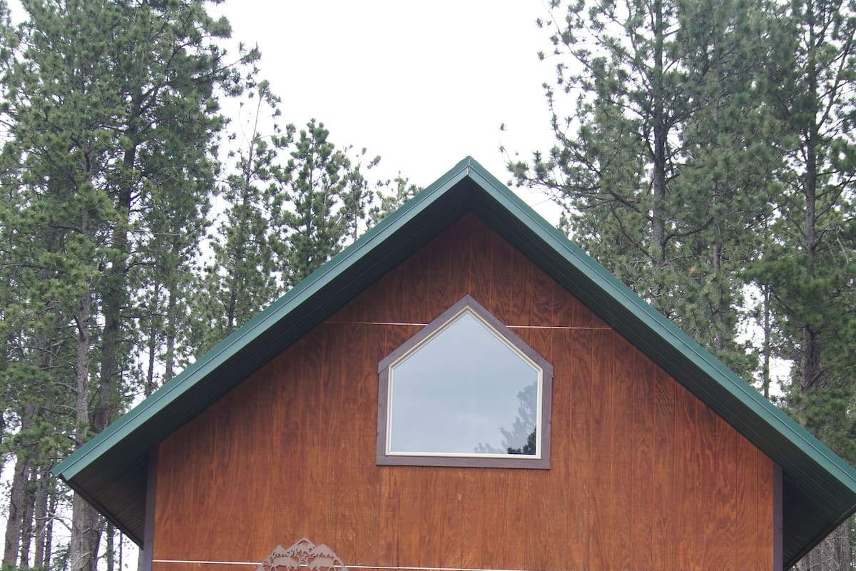 Una cabaña de madera con balcón, una puerta y una ventana.