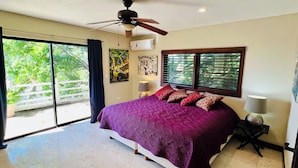 A spacious bedroom with a large bed, a ceiling fan, and a view of greenery through the windows. - Stunning Rooftop Villa with Breathtaking Caribbean Views & Large Private Terrace (San Miguel de Cozumel)