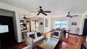 A spacious living area with wicker furniture, ceiling fans, and a view of the ocean. - Stunning Rooftop Villa with Breathtaking Caribbean Views & Large Private Terrace (San Miguel de Cozumel)