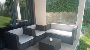 A patio with wicker furniture, including a sofa and chairs, and a small table. - COZY GUEST HOUSE (BUEU)