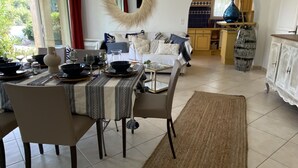 Ruime eethoek met een ronde spiegel, een gedekte tafel voor vier personen en een keuken op de achtergrond.