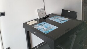 A conference room with a glass table, two chairs, a flat-screen TV mounted on the wall, and a small window with a decorative item. - Studio near the beach (Criel-sur-Mer)