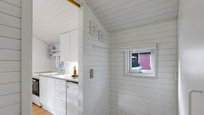 Ein schmaler Korridor mit weißen Holzwänden und einem kleinen Fenster.