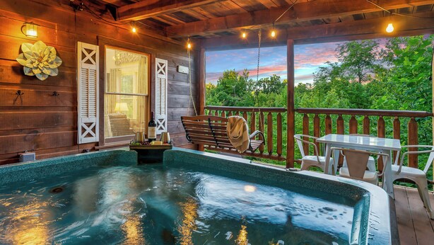 A wooden deck with a hot tub, outdoor seating, and a view of trees. - Hot tub cabin near Pigeon Forge, game room, mountain views (Sevierville)