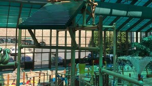 A water feature with a wooden barrel labeled "Wild Falls" in a covered area with a glass ceiling.