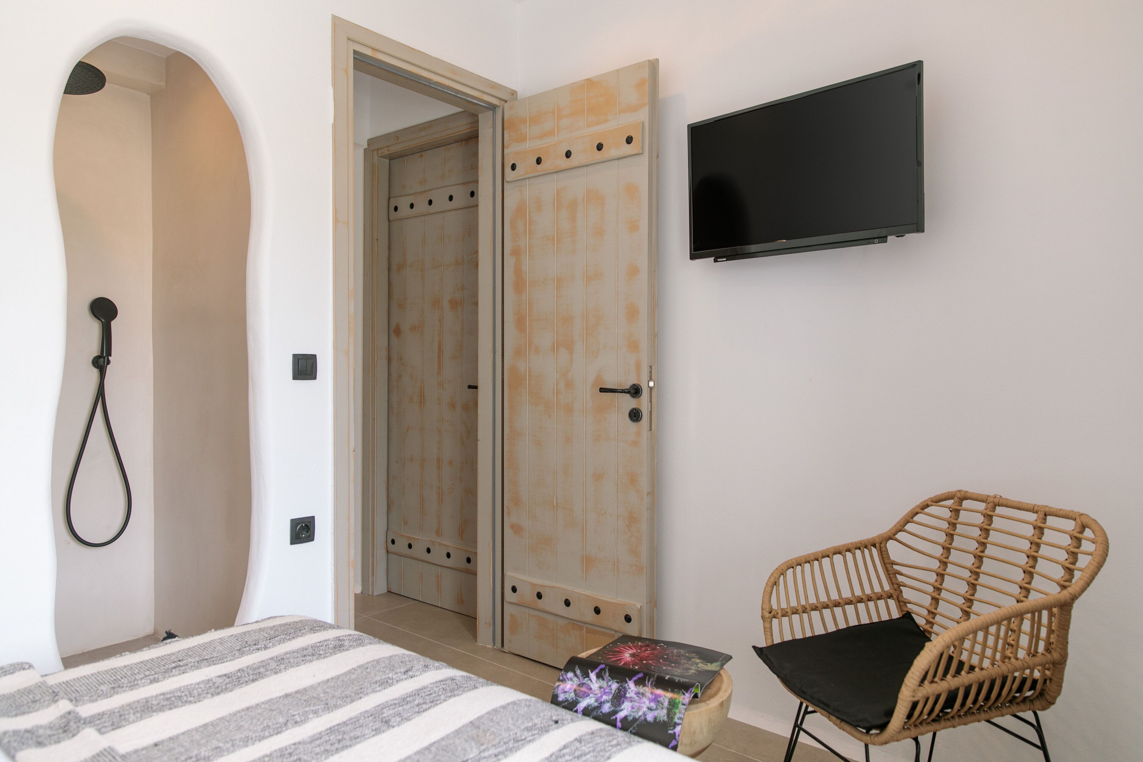 Ein Schlafzimmer mit einem Bett, einem Fernseher, einem Korbstuhl und einem Holzschrank.