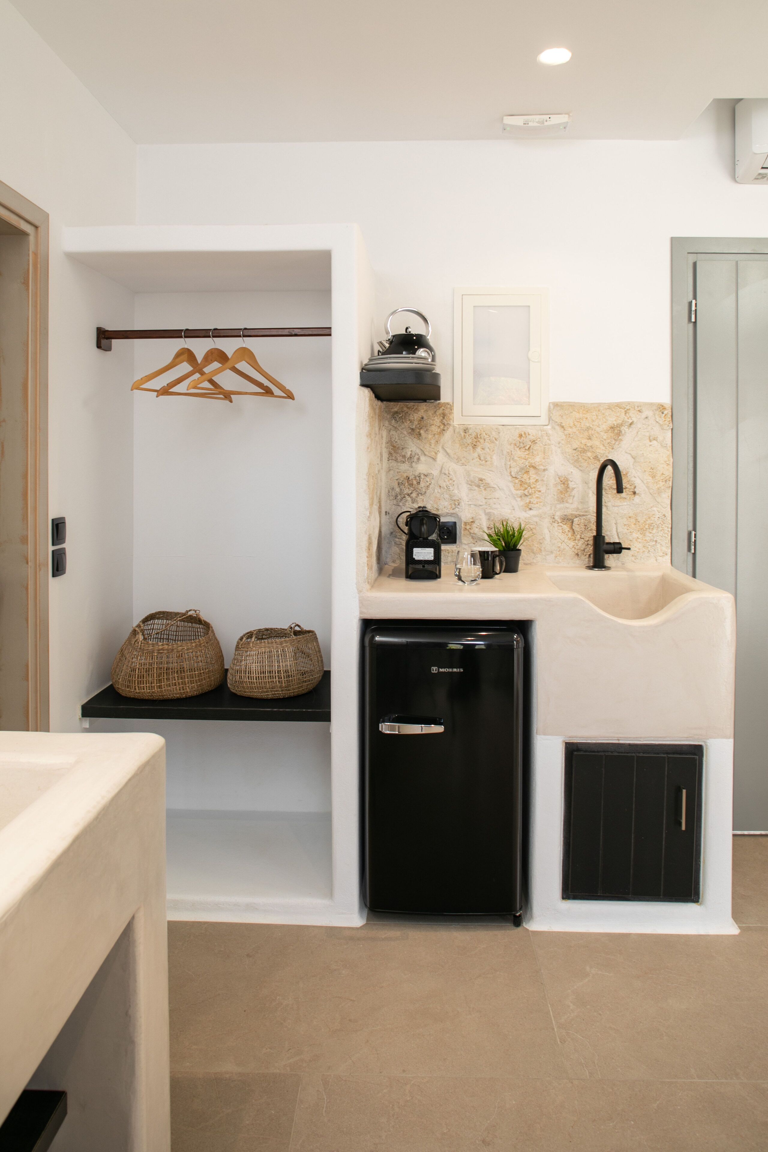 Una cocina compacta con un lavamanos integrado, cafetera y un refrigerador pequeño.