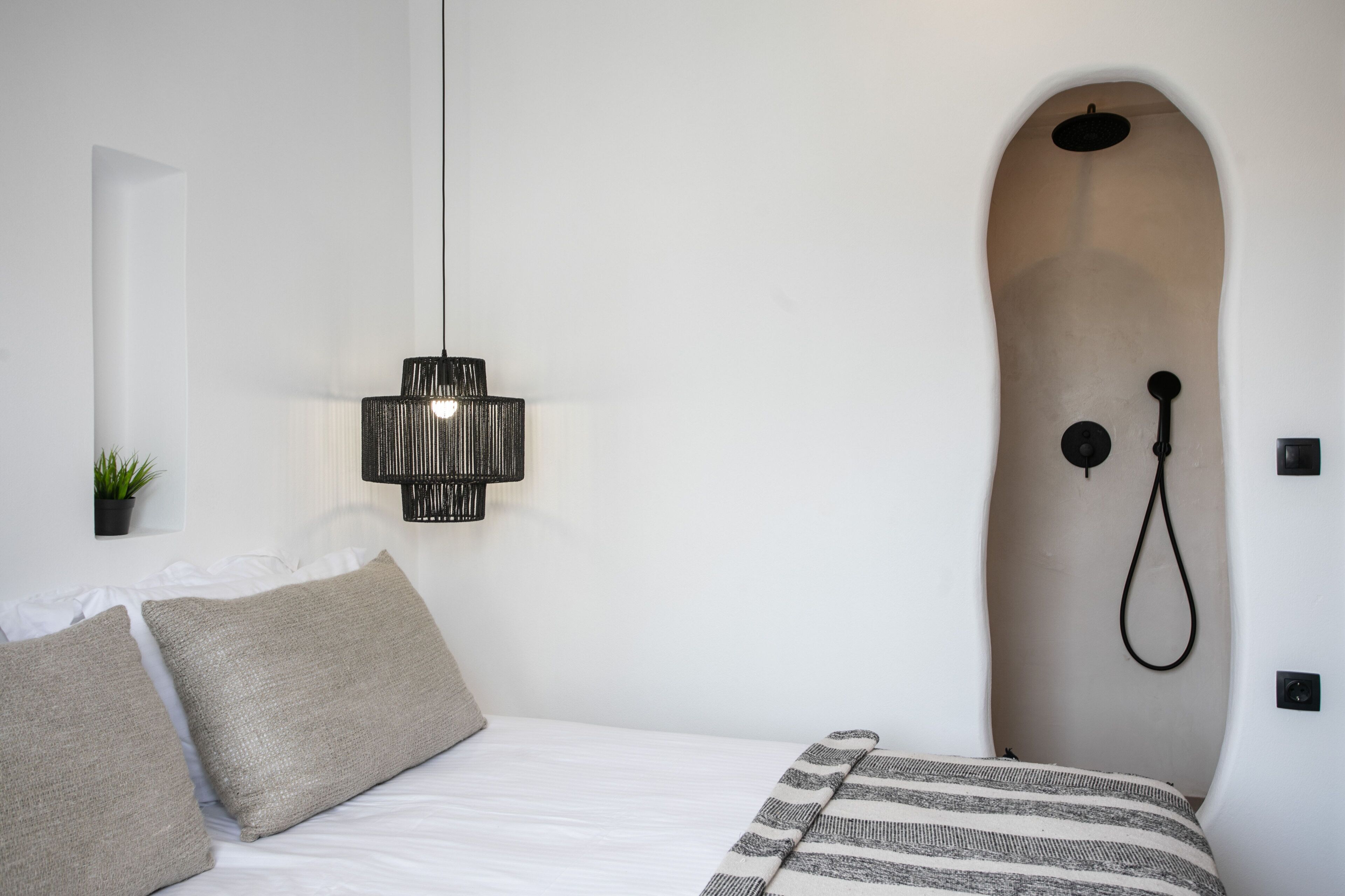 Ein Schlafzimmer mit Bett, einer Pendelleuchte und einer Duschkabine.