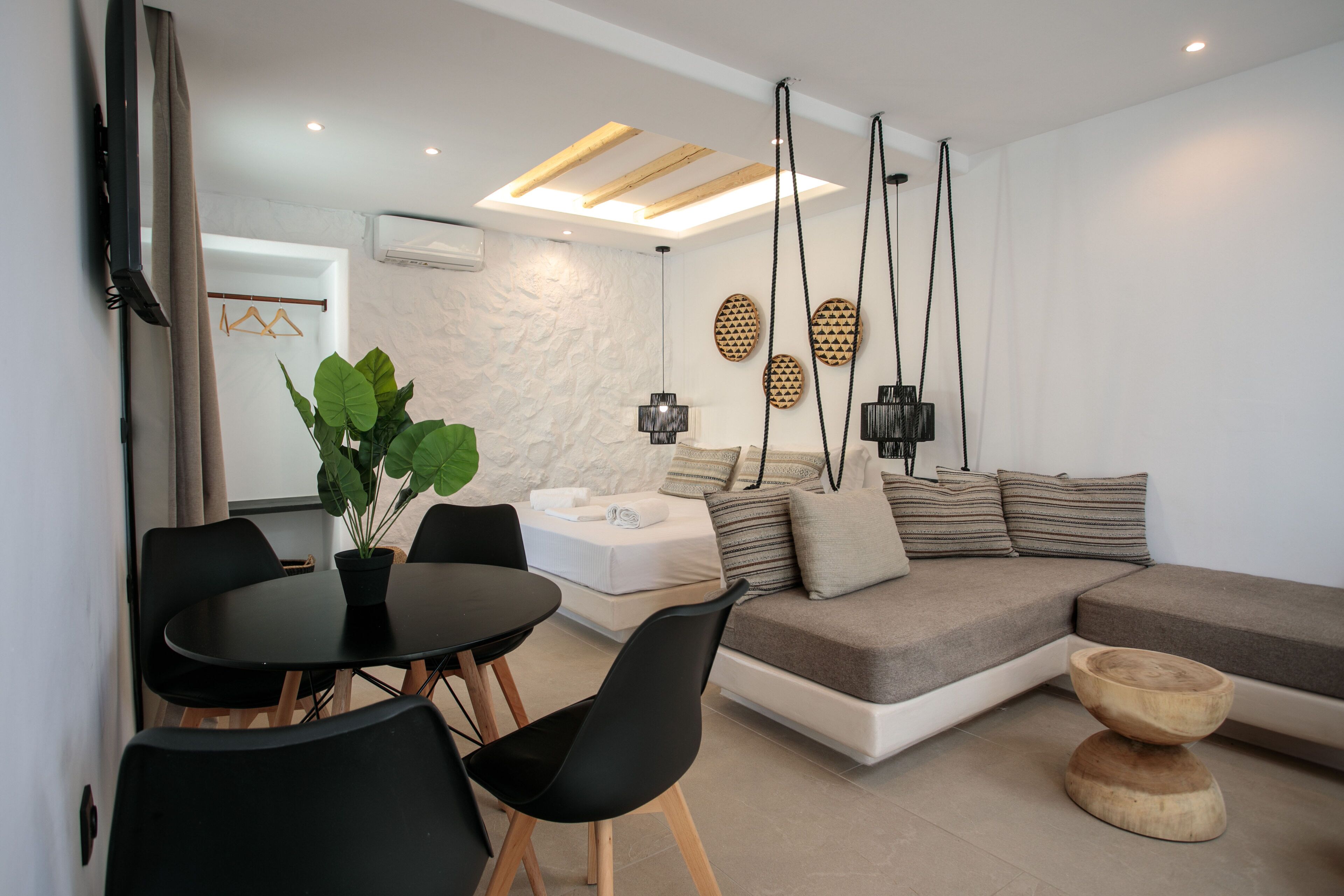 Un salon moderne avec un canapé d’angle, une table à manger avec des chaises et une plante en pot.