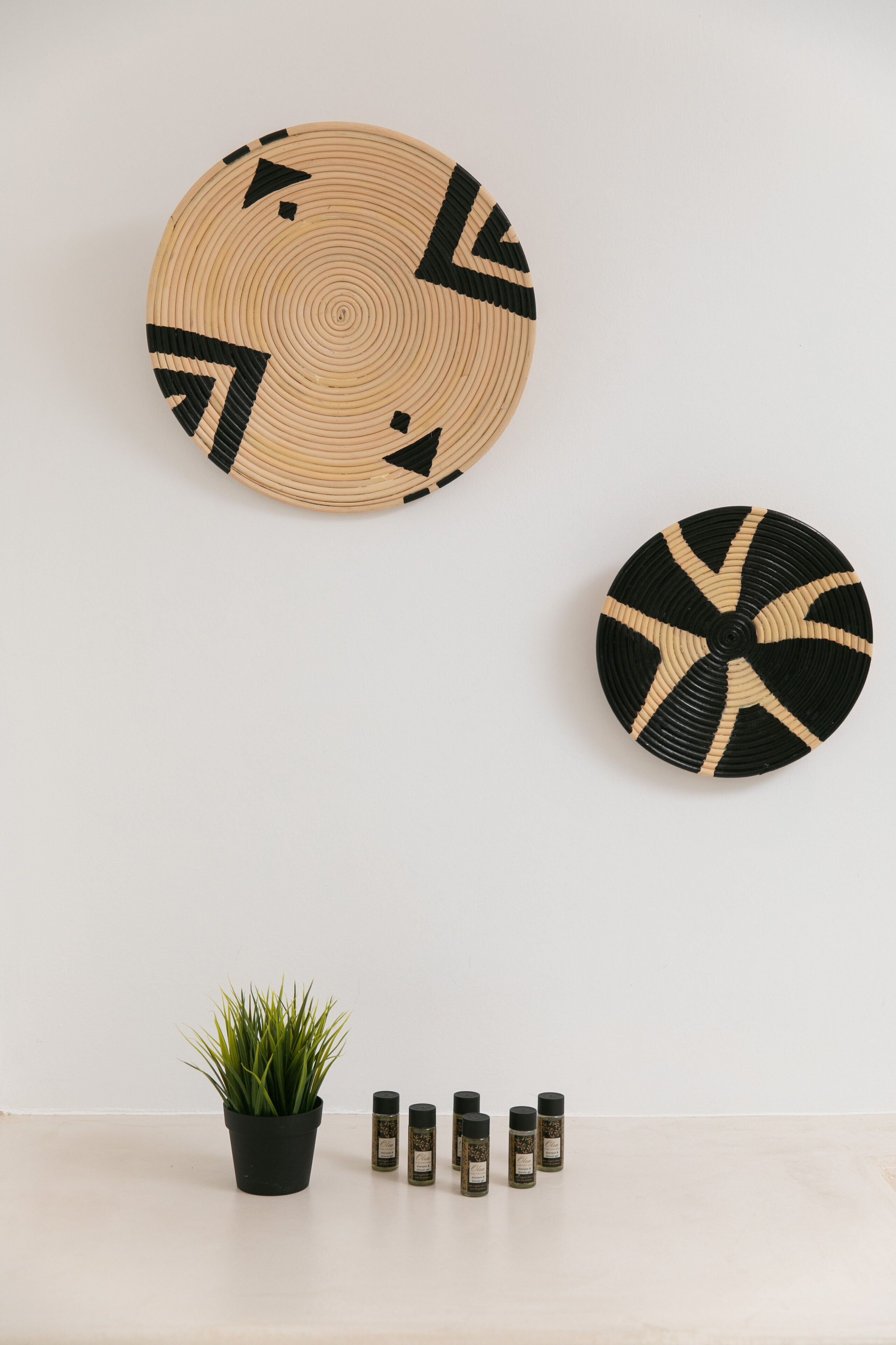 Two woven wall hangings and a potted plant with spice bottles on a table.