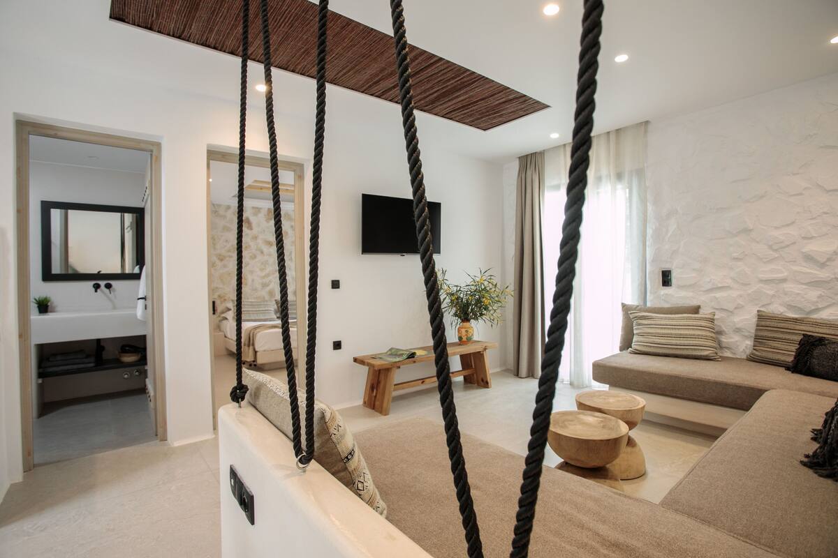 A modern living room with a sofa, coffee table, and a hanging rope swing.