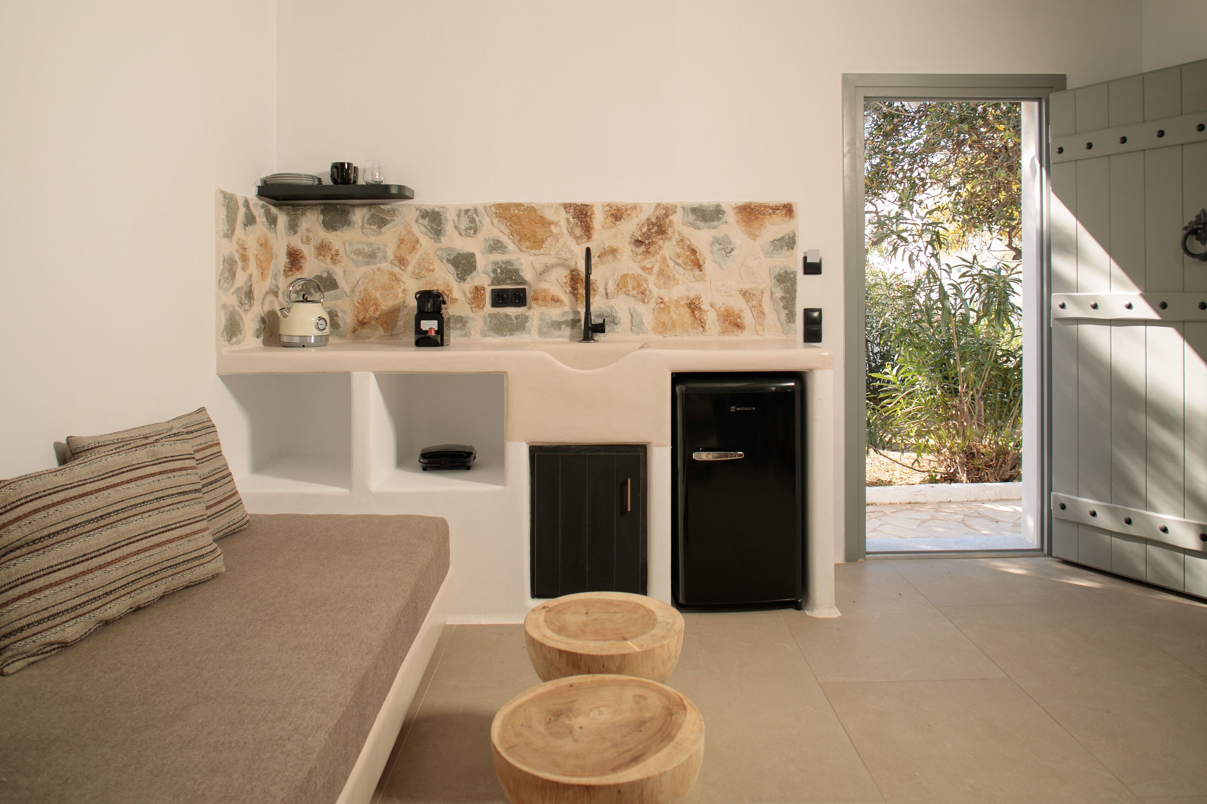 A modern kitchen with a stone backsplash, a built-in refrigerator, and a dining area with a bench and stools.