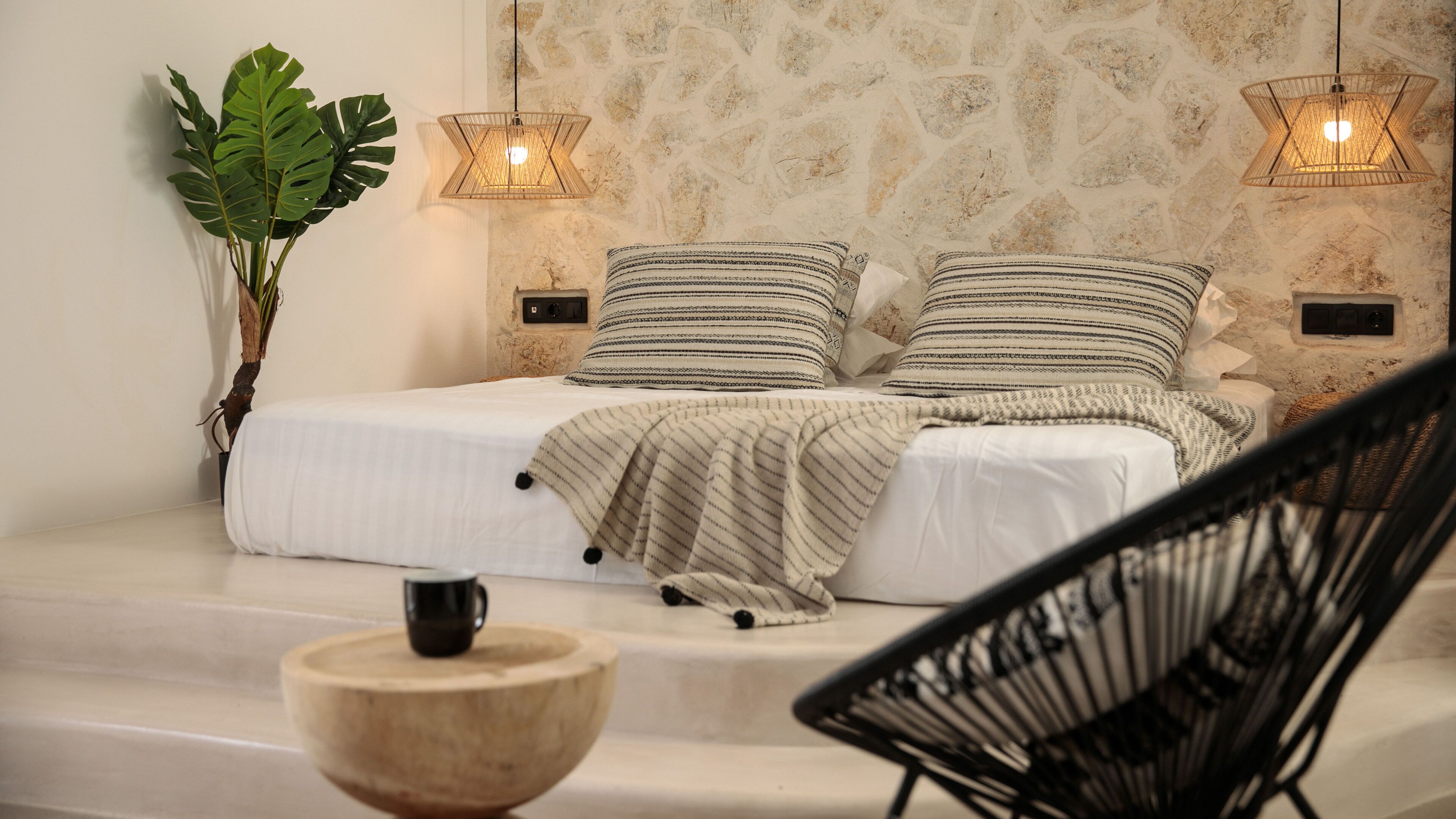 Un dormitorio moderno con una cama, dos mesitas de noche, una planta en maceta y una silla.