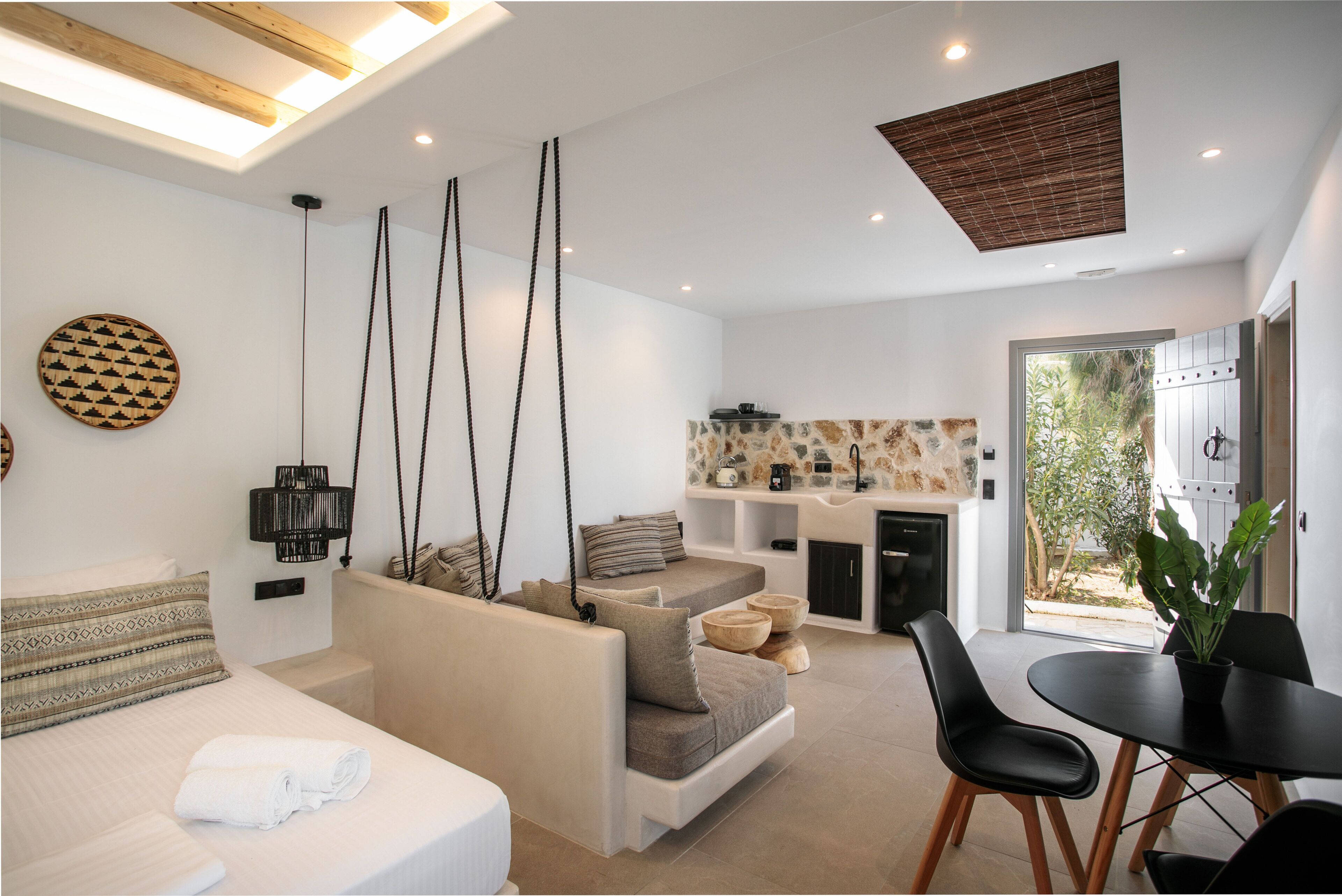 A modern living room with a sofa, a dining table, and a kitchen area.
