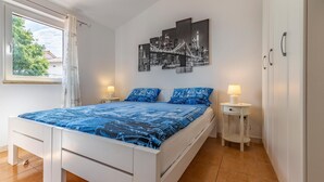 A bedroom with a bed, two bedside tables, a window, and a cityscape artwork on the wall. - 2 bedroom beautiful apartment in Premantura (Premantura)