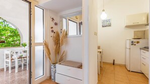 A compact kitchen with white cabinets, a refrigerator, and a dining area with a table and chairs. - 2 bedroom beautiful apartment in Premantura (Premantura)