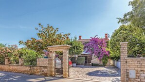 A gated entrance with a stone archway, a cobblestone driveway, and a building with a tiled roof and satellite dish. - 2 bedroom beautiful apartment in Premantura (Premantura)