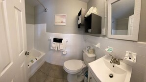 Un baño con inodoro, lavabo y ducha. Hay un toallero y un espejo sobre el lavabo.