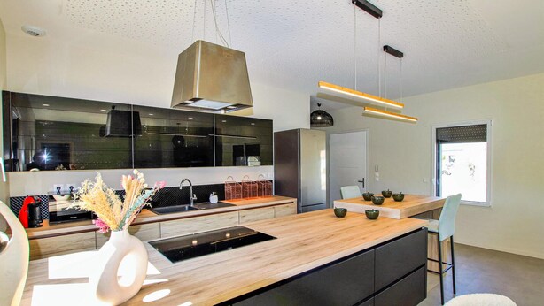Een moderne keuken met een centraal eiland, roestvrijstalen apparatuur en een groot raam dat voor natuurlijk licht zorgt.