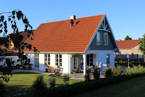 Een huis met een rode pannendak, witte buitenmuren en een blauwe accentkleur.