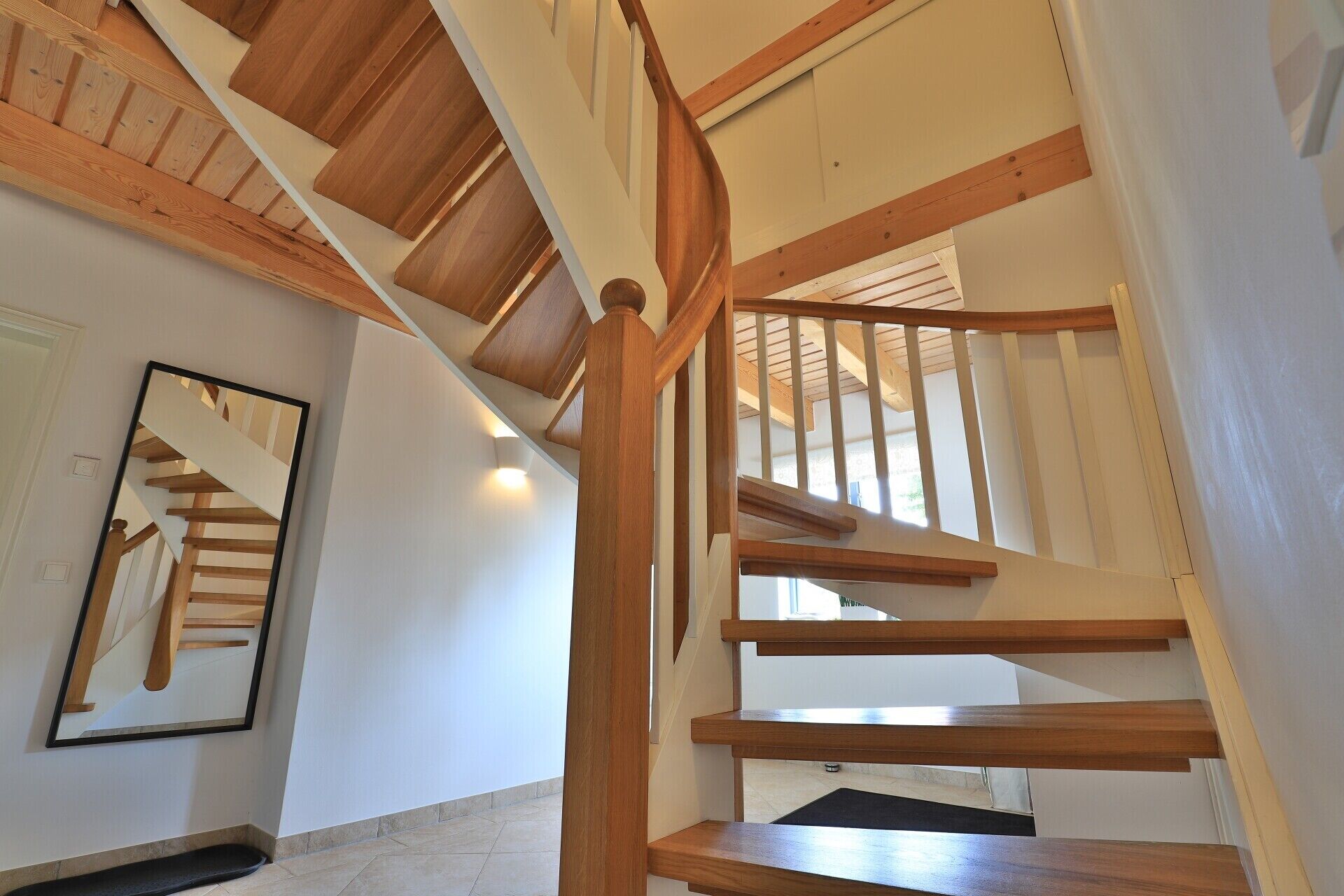 Un escalier en colimaçon avec des marches en bois et une rampe, menant à l’étage supérieur.