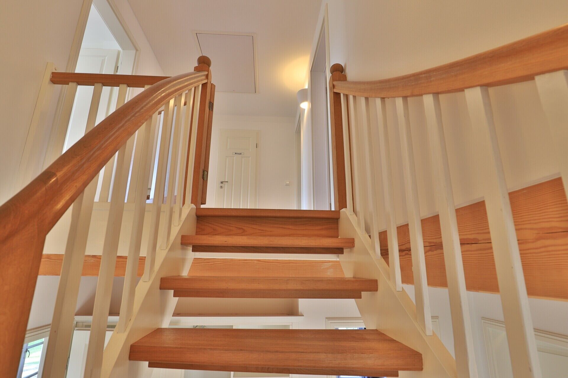 Un escalier en bois, avec des rampes blanches, mène à une porte portant l’inscription « Privé ».