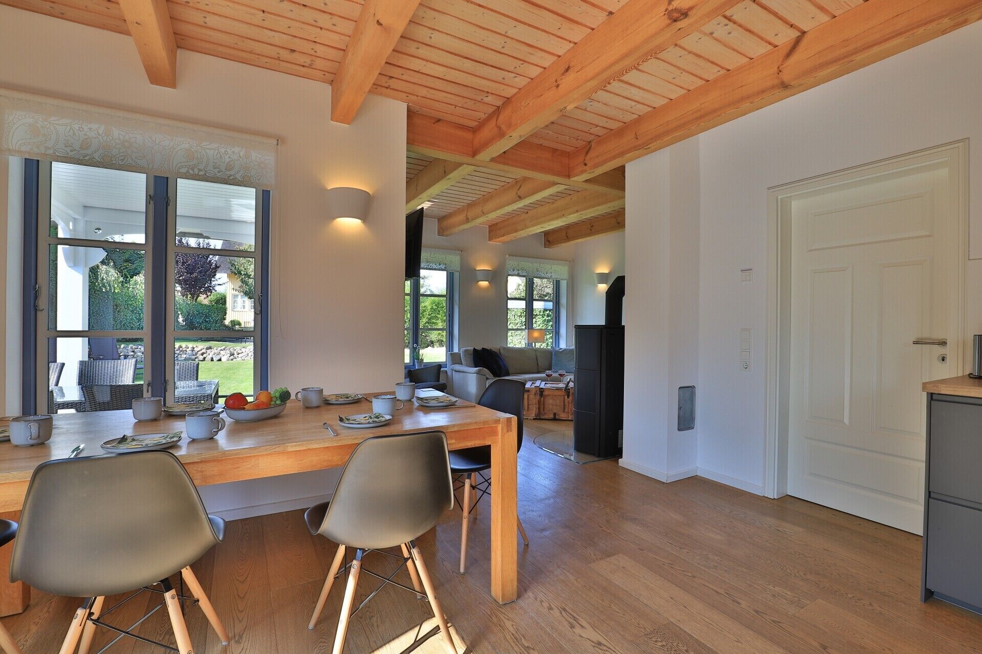 Eine moderne Küche mit Holzbalken, einem Essbereich mit Stühlen und Blick ins Freie.