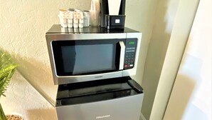 A compact kitchen setup with a microwave and a Hisense refrigerator. - Quaint Queen Deluxe (Daytona Beach)