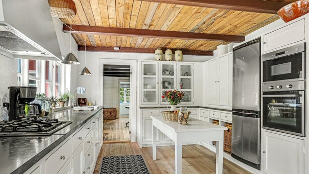 A modern kitchen with white cabinetry, stainless steel appliances, and a wooden ceiling. - 3 bedroom cozy home in Hals (Hals)