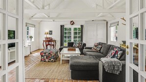 A spacious living room with a fireplace, a dining area with a table and chairs, and a large window with curtains. - 3 bedroom cozy home in Hals (Hals)