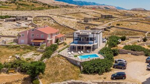 Una villa moderna con piscina, circondata da mura in pietra e con le montagne sullo sfondo.