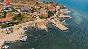 Una vista aerea di un villaggio costiero con case, un porto turistico e acque blu cristalline.