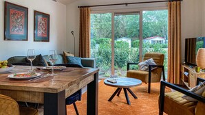 Un coin repas avec une table en bois, des chaises et une vue sur un jardin grâce à de grandes fenêtres.