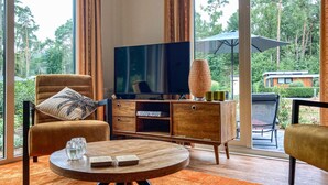 Un salon moderne avec un téléviseur, des meubles en bois et une vue sur l’extérieur.