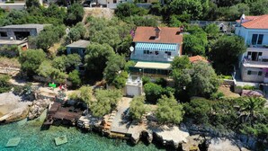 Eine Küstenimmobilie mit einem Haus, das ein Ziegeldach, einen Poolbereich und einen Steinweg zum Wasser hat.